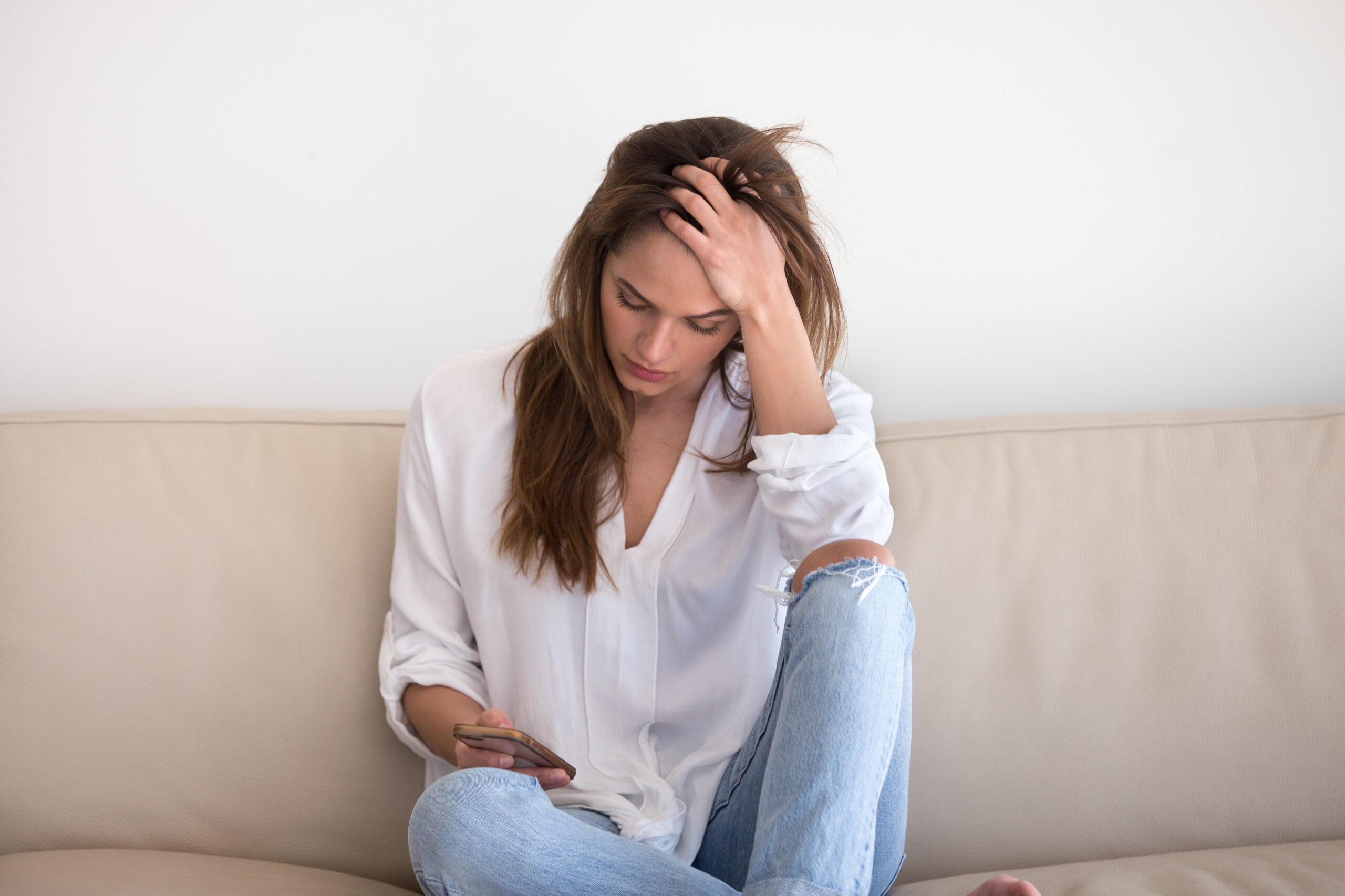 a woman looks sadly at her phone after her infant adoption failed